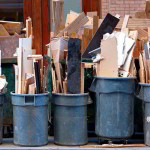 Row of garbage bins with construction debris on sidewalk